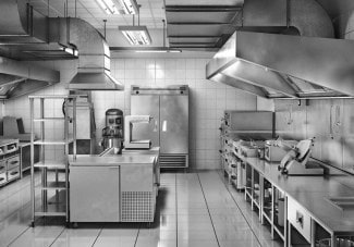 Monochrome photo of a spacious, clean commercial kitchen with warewashing equipment.